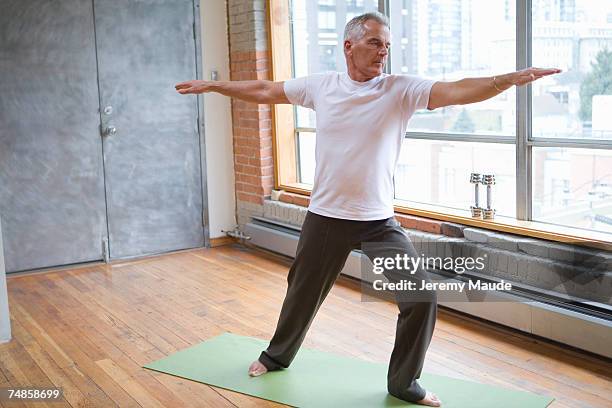 senior man doing exercise in gym, arms out - senior yoga stock-fotos und bilder