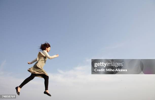 young woman running against blue sky - 走る　女性 ストックフォトと画像