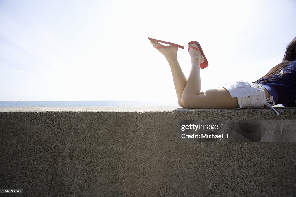 Young woman lying on breakwater, side view