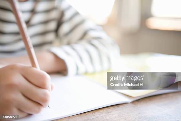 boy (8-9) writing in class, close-up - escritores fotografías e imágenes de stock