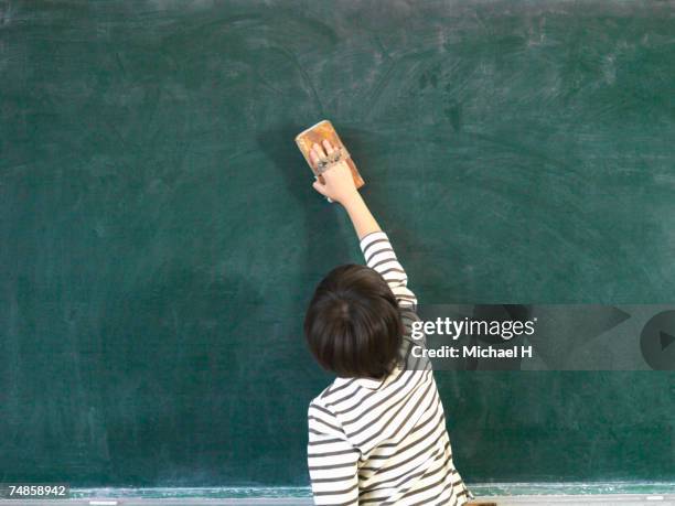 boy (6-7) cleaning blackboard in classroom - schulkind nur jungen stock-fotos und bilder