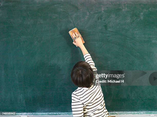 boy (6-7) cleaning blackboard in classroom - schoolboy stock pictures, royalty-free photos & images