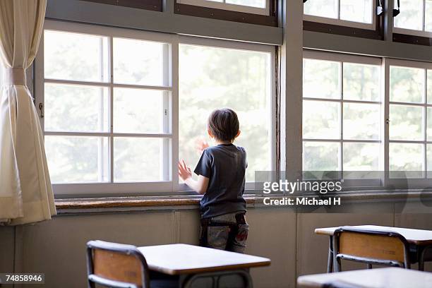 boy (6-7) looking out of classroom window, rear view - japanese elementary school bildbanksfoton och bilder