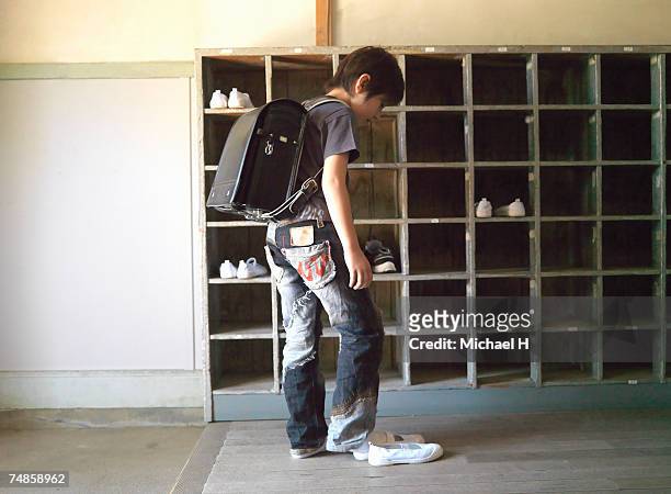 boy (6-7) changing shoes at school - young boys changing in locker room imagens e fotografias de stock
