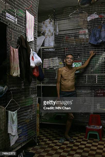 Mr Kong, a cage dweller stands in front of cages on June 20, 2007 in Hong Kong, China. The poorest of Hong Kong's citizens live in cage homes, steel...