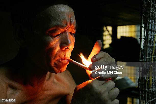 Mr Kong, a cage dweller smokes inside a cage on June 20, 2007 in Hong Kong, China. The poorest of Hong Kong's citizens live in cage homes, steel mesh...