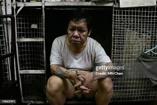 Mr Jau, a cage dweller sits inside a cage on June 20, 2007 in Hong Kong, China. The poorest of Hong Kong's citizens live in cage homes, steel mesh...