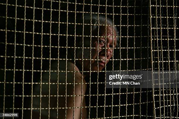 Cage dweller sits inside a cage on June 20, 2007 in Hong Kong, China. The poorest of Hong Kong's citizens live in cage homes, steel mesh box...