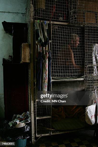 Cage dweller sits inside a cage on June 20, 2007 in Hong Kong, China. The poorest of Hong Kong's citizens live in cage homes, steel mesh box...