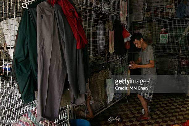 Mr Chan, a cage dweller stands beside cages on June 20, 2007 in Hong Kong, China. The poorest of Hong Kong's citizens live in cage homes, steel mesh...