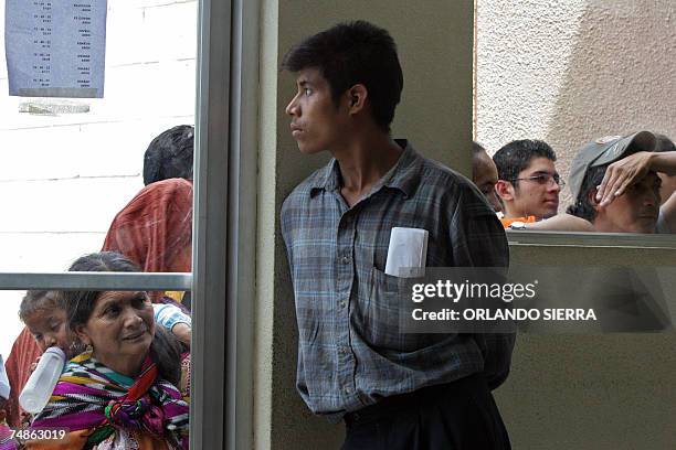 Guatemala City, GUATEMALA: Un inmigrante observa a traves de una puerta de vidrio al ser deportado de los Estados Unidos y arribar a la Fuerza Aerea...