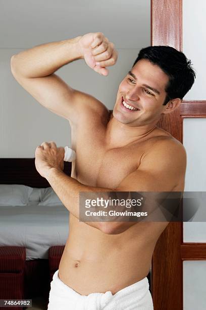 young man applying deodorant under his armpit - deodorant photos et images de collection