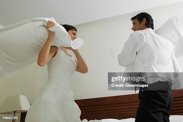 newlywed couple having a pillow fight on the bed - naughty bride stock pictures, royalty-free photos & images