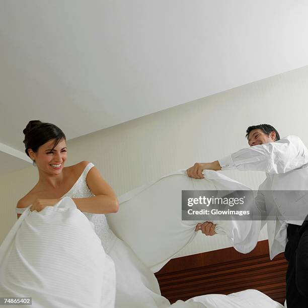 newlywed couple having a pillow fight on the bed - naughty bride stock pictures, royalty-free photos & images