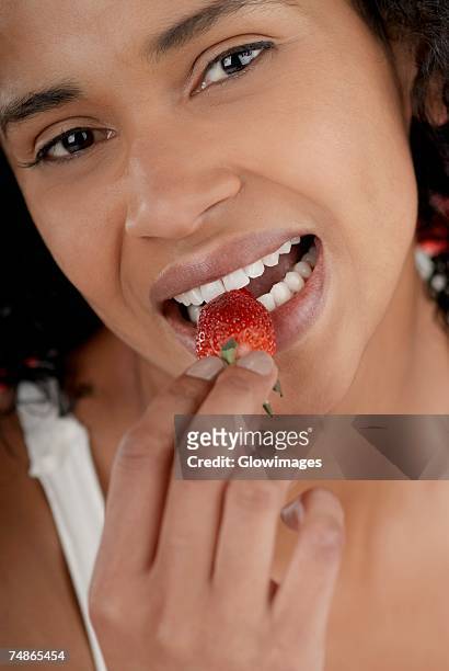 portrait of a young woman eating a strawberry - juicy lips stock pictures, royalty-free photos & images