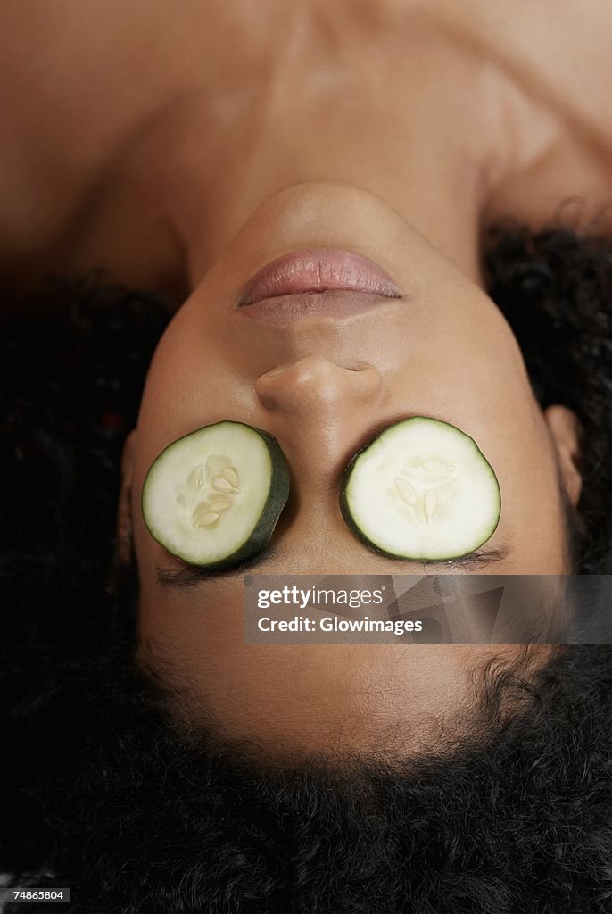 Close-up of a young woman with cucumber slices on her eyes