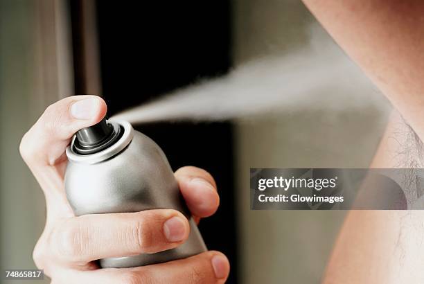 mid section view of a young man spraying deodorant - man spraying stock pictures, royalty-free photos & images