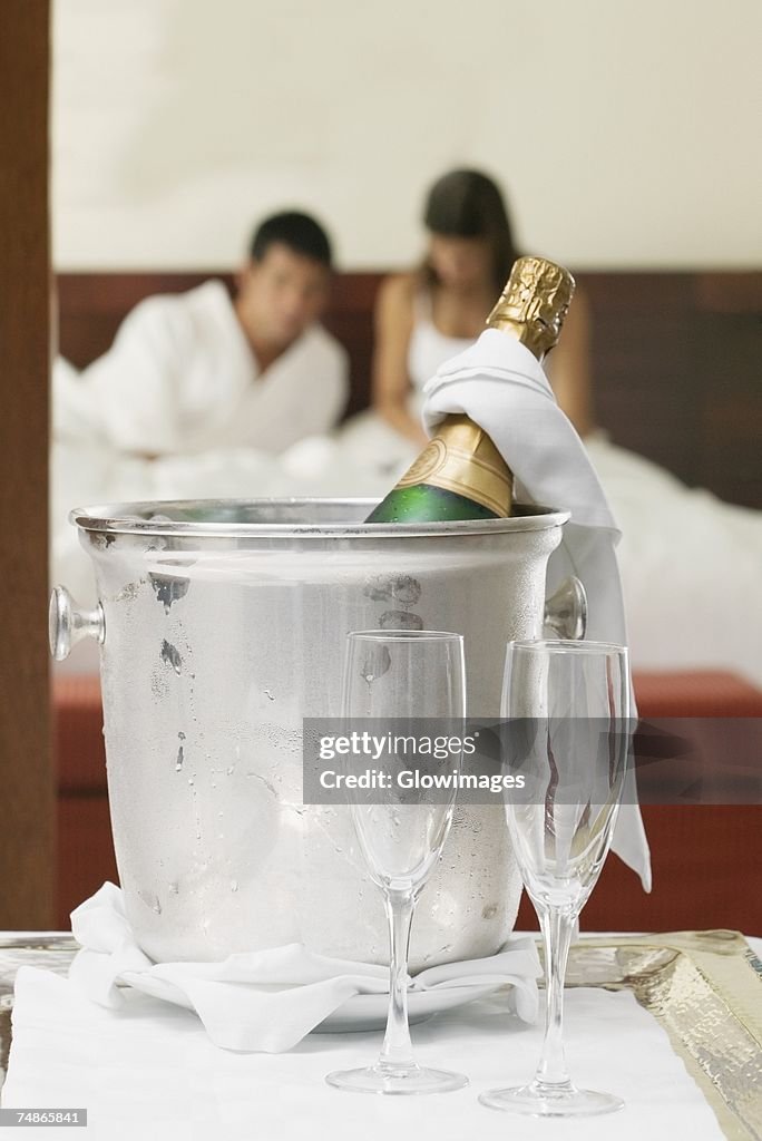 Close-up of a champagne bottle in an ice bucket with two champagne flutes