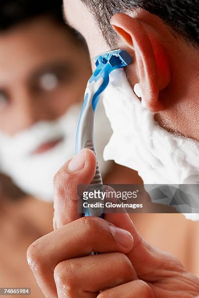 close-up of a young man shaving - man shaving face stock-fotos und bilder
