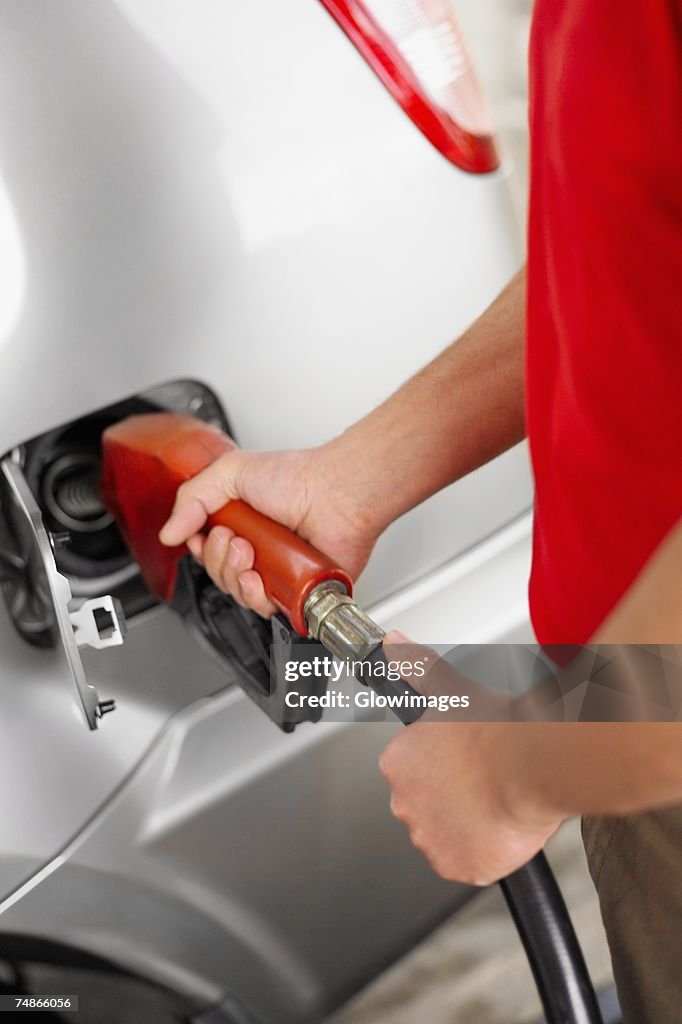 Mid section view of a man refueling a car