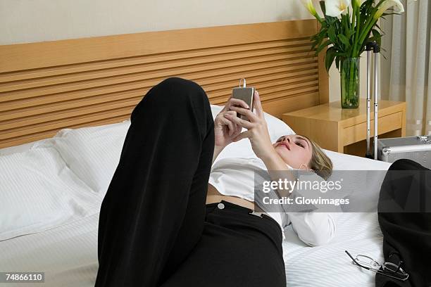 close-up of a businesswoman lying on the bed listening to an mp3 player - woman back pillow blonde stock pictures, royalty-free photos & images