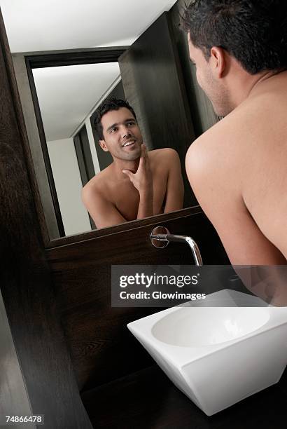 close-up of a young man looking into a mirror and smiling - rear view mirror stockfoto's en -beelden