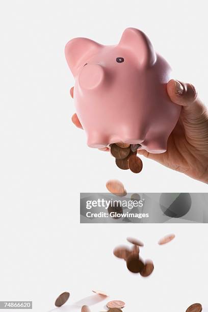 close-up of a person dropping coins from a piggy bank - smashed piggy bank stock pictures, royalty-free photos & images
