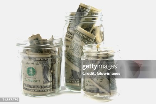 Dollar bills squashed into three jars Dollar bills squashed into three jars