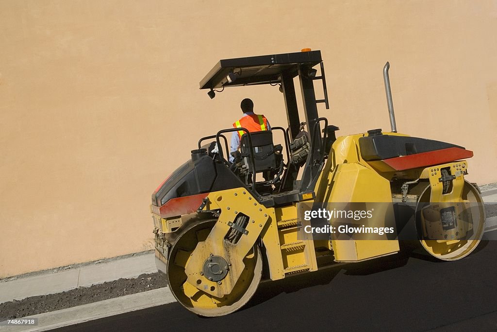 Rear view of a man sitting on a steamroller