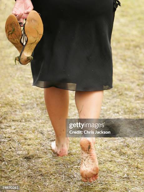 Woman carries her heeled shoes as she walks barefoot on the wet grass as rain continues to fall at Royal Ascot on June 23, 2007 in Ascot, Berkshire...