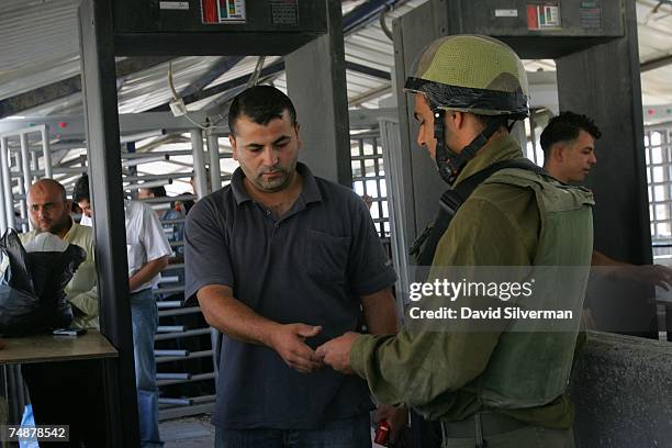 Palestinian men go through metal detectors and identity checks at the Israeli army checkpoint June 25, 2007 at Hawarra on the outskirts of the West...