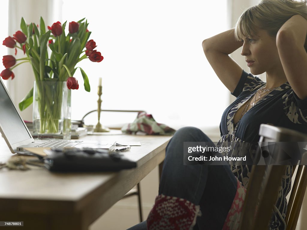 Young woman sitting at laptop on dining table