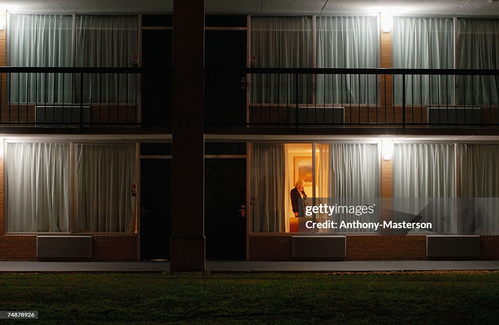 Woman in motel room, view through window, night