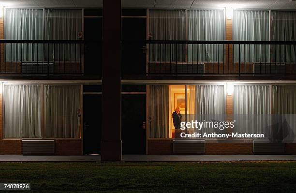 woman in motel room, view through window, night - motel stockfoto's en -beelden