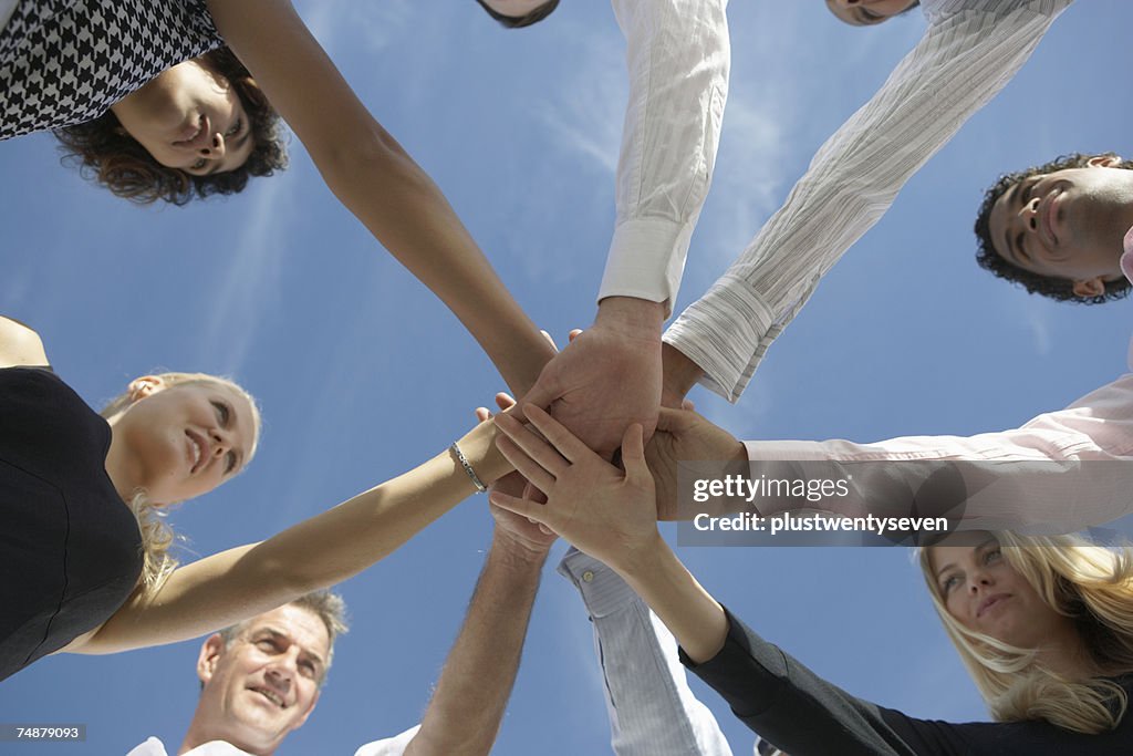 Group of people holding hands in circle, low angle view