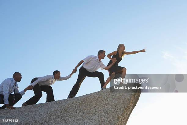 woman leading three colleagues on rock, pointing - rocky point stock pictures, royalty-free photos & images