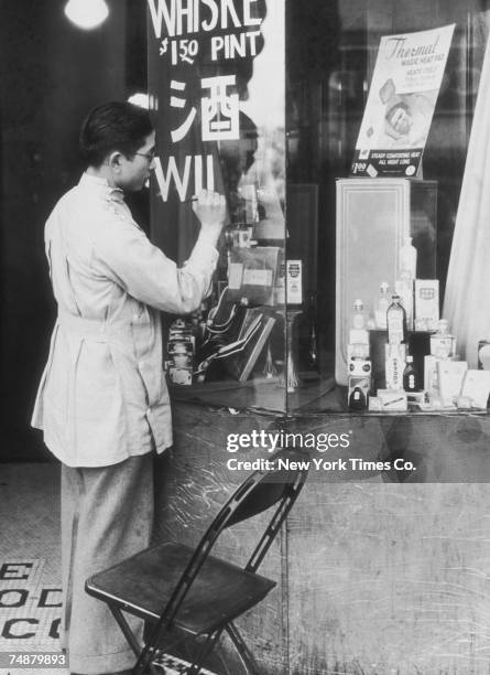 Liquor merchant in the Chinatown area of Los Angeles marks up the price of a pint of whiskey in English and Chinese at the end of prohibition, 5th...