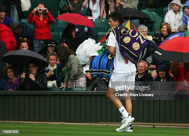 Tim Henman of Great Britain walks off Centre Court as the rain starts to fall during his Men's Singles first round match against Carlos Moya of Spain...