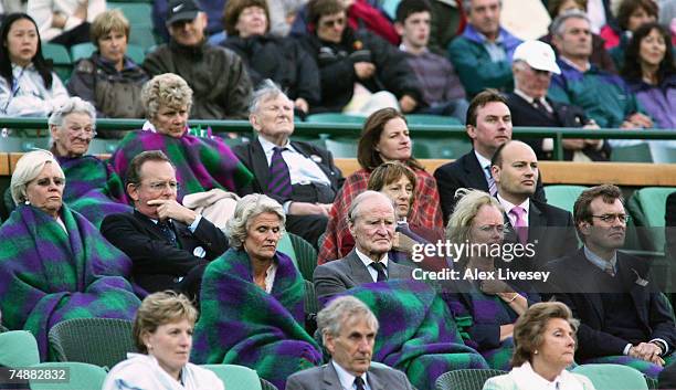 Spectators keep warm during the Men's Singles first round match between Tim Henman of Great Britain and Carlos Moya of Spain during day one of the...