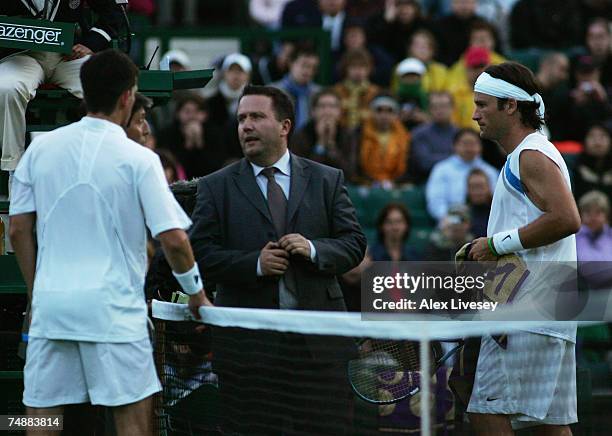 Officials discuss the possible end of play due to bad light as Tim Henman of Great Britain and Carlos Moya of Spain during his Men's Singles first...