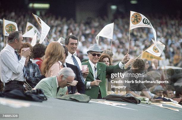 Oakland Athletics owner Charles Finley waves a banner as he watches Game 5 of the World Series against the Los Angeles Dodgers with Rock Hudson and...