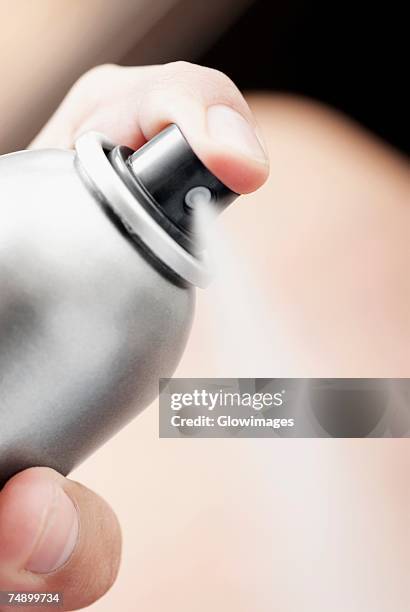 close-up of a person's hand spraying deodorant - deodorant photos et images de collection
