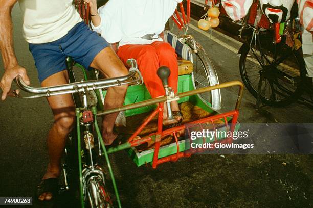 low section view of a rickshaw driver pulling a rickshaw, singapore - rickshaw or tuk tuk or surrey or pedicab stock pictures, royalty-free photos & images