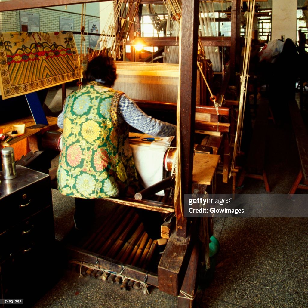 Rear view of a person weaving silk on a loom, Nanjing, Jiangsu Province, China