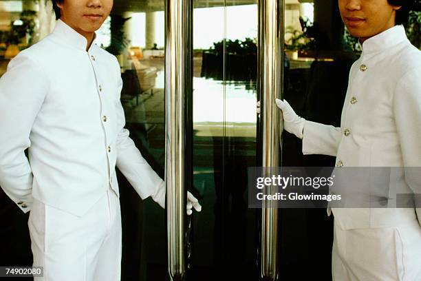 two porters standing at the entrance of a hotel doors, regent hotel, kowloon, hong kong, china - door attendant stock pictures, royalty-free photos & images