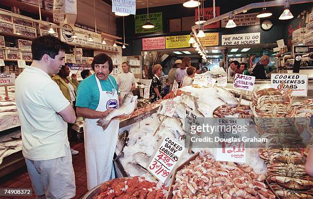 Shoppers check out the fresh seafood at Purefood Fish Market at Pike Place Market.The open-air market is in downtown Seattle.