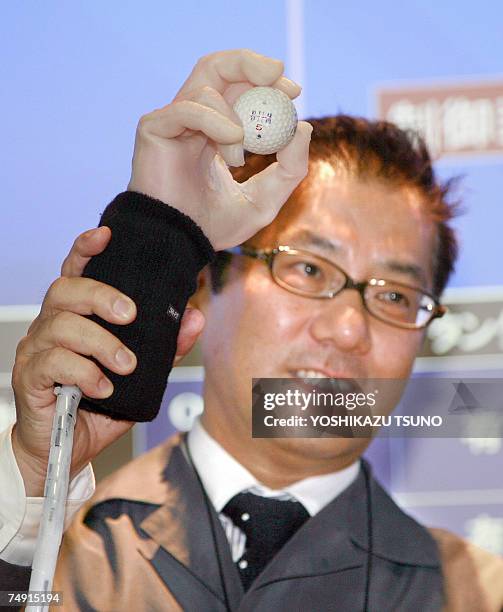 An employee of Japanese robot venture Squse, displays a portable robot hand which can hold a golf ball, in Tokyo 26 June 2007. The human-sized...
