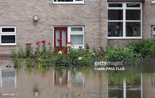 Woman looks out the window at her flooded yard in Hull, northeast England, 26 June 2007. Hundreds of people in northern England were evacuated from...