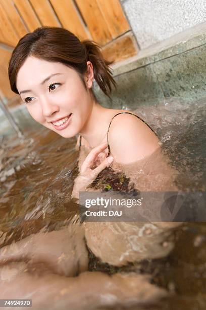 woman in a bathing suit relaxing in a hot tub,  smiling, side view, japan - thermal suit stockfoto's en -beelden