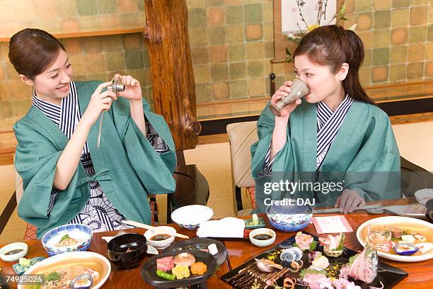 two women having dinner, one taking a picture, front view, japan - yukata stock pictures, royalty-free photos & images